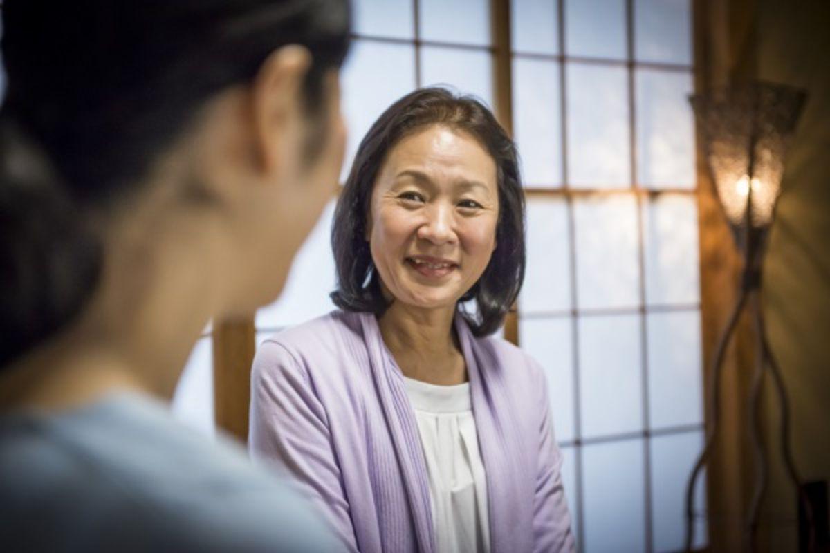 Asian patient conversing and smiling with doctor.